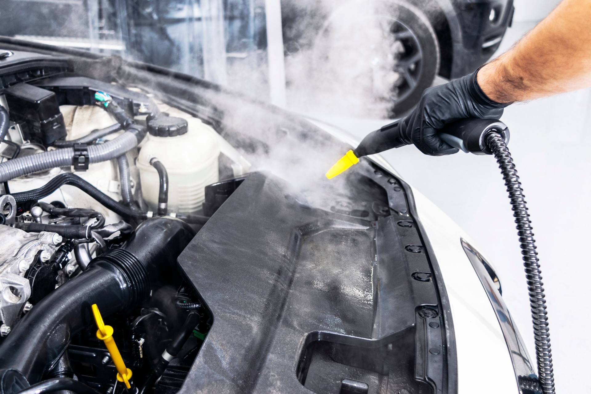 Car detailing. Car washing cleaning engine. Cleaning car using hot steam. Hot Steam engine washing. Soft lighting. Car wash man worker cleaning vehicle.